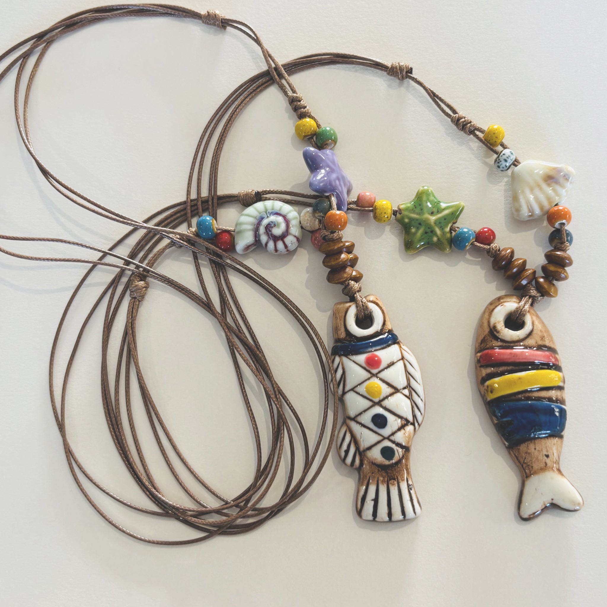 Colorful fish-shaped ceramic pendants on a cord necklace with beads