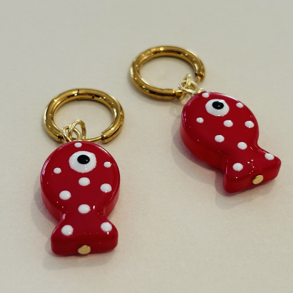 Two red fish-shaped earrings with white polka dots and gold rings