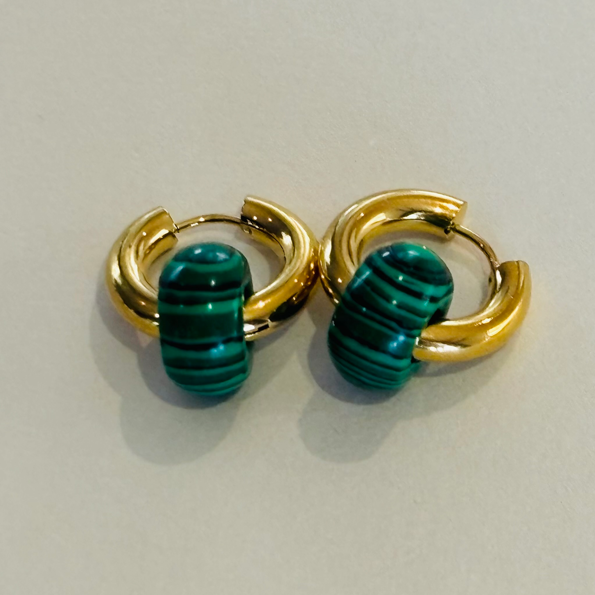 Pair of gold hoop earrings with green striped stones
