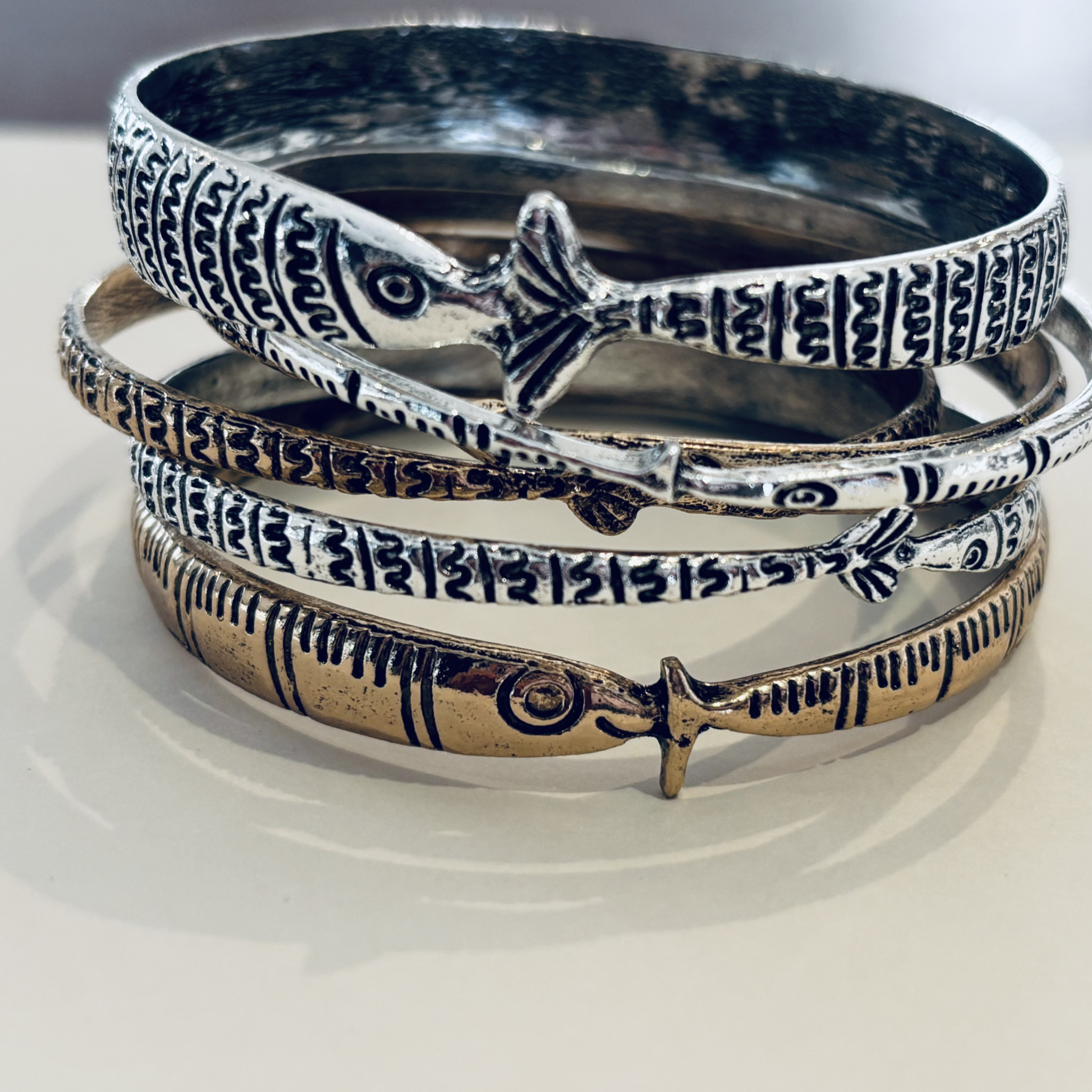 Stack of silver bangles with intricate designs