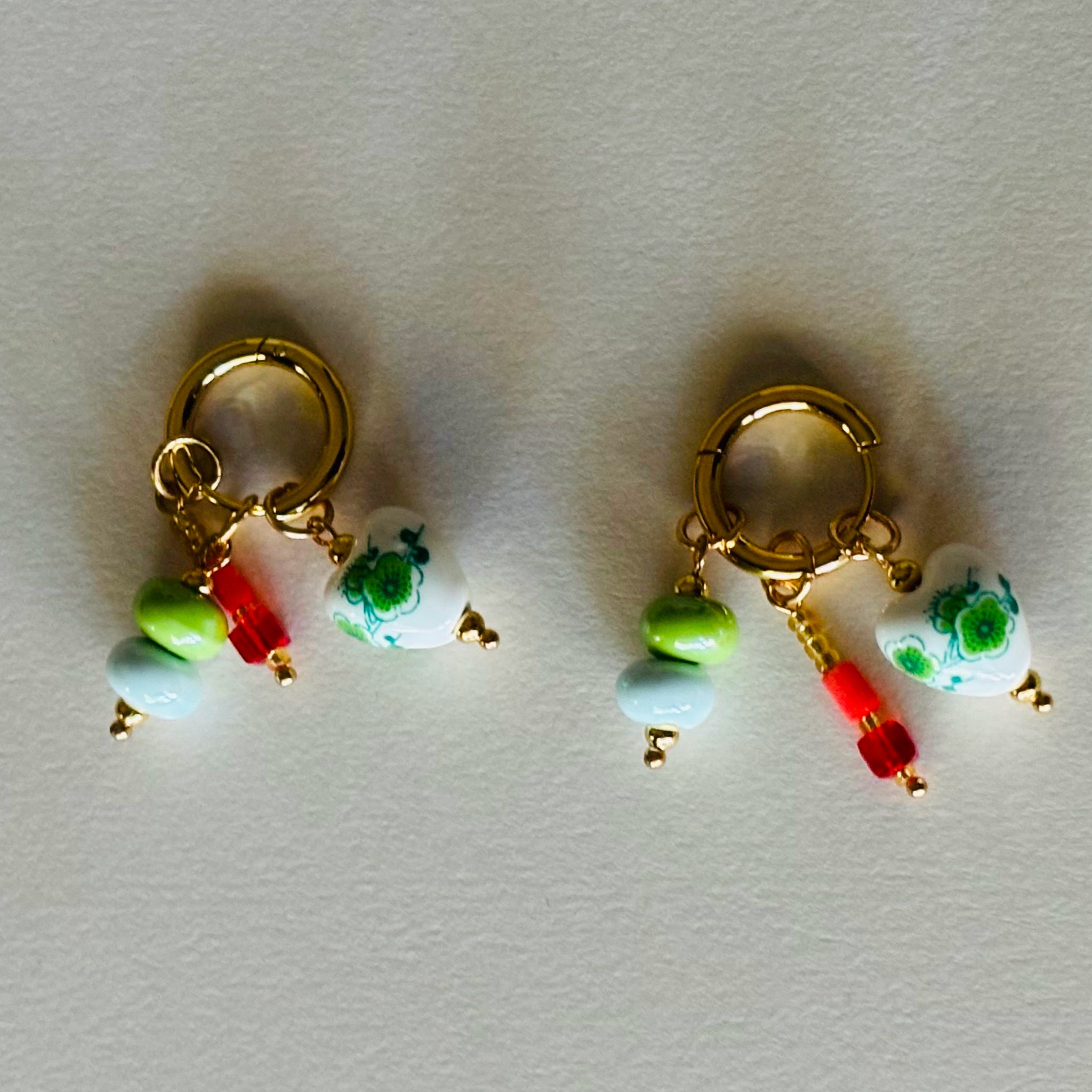 Pair of gold earrings with colorful beads and charms