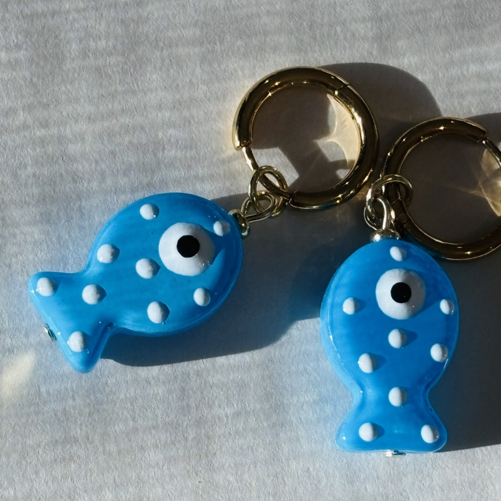 Two blue fish-shaped earrings with white spots
