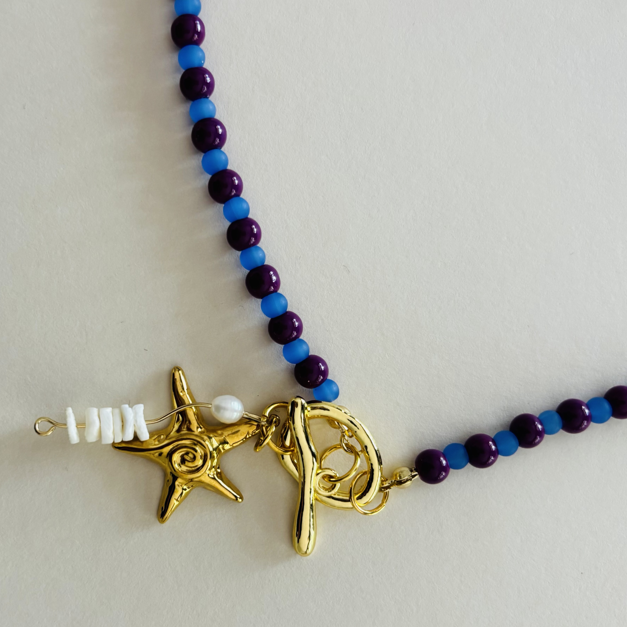 Necklace with blue and purple beads and gold starfish charms 