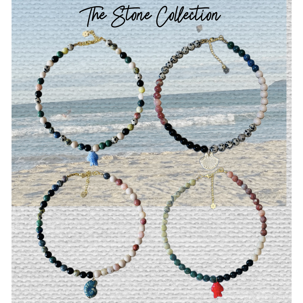 Set of beaded necklaces with charms on a textured surface with 'The Stone Collection' text.